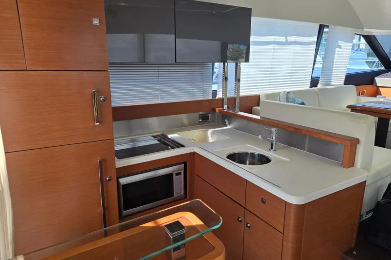 What A Day Yacht Photos Pics Modern kitchen interior on 2013 Prestige 500 yacht, featuring sleek wood cabinetry and stainless steel appliances.