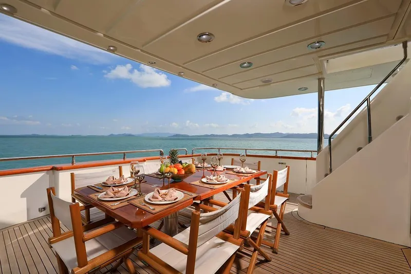 Demarest Yacht Photos Pics Luxurious Falcon 106 yacht deck with dining setup, ocean view, and elegant wooden furniture, 2002 model.