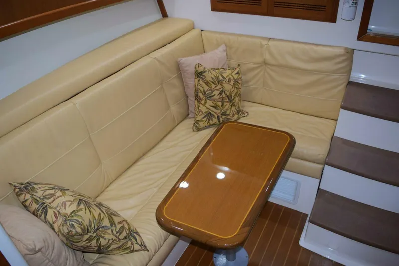Never Again VII Yacht Photos Pics 2006 Cabo 35 Express interior with beige seating, wooden table, and decorative pillows.