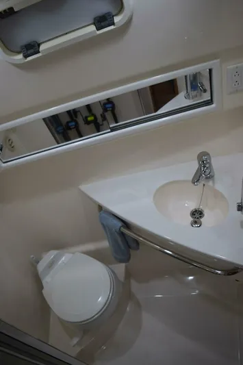 Never Again VII Yacht Photos Pics Bathroom interior of 2006 Cabo 35 Express boat with sink, mirror, and toilet.