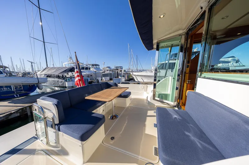 Yacht Photos Pics 2021 Sabre Salon Express yacht deck with blue seating and wooden table at marina.