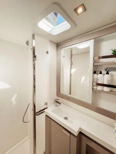 Sea The World Yacht Photos Pics Modern bathroom interior of 2023 Fountaine Pajot Elba 45 yacht, featuring sleek design and skylight.