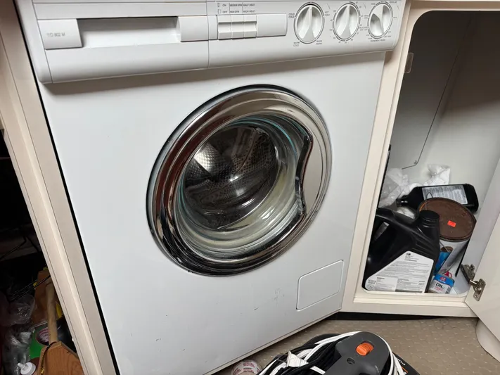  Yacht Photos Pics Front-loading washing machine in a cabinet, surrounded by cleaning supplies.
