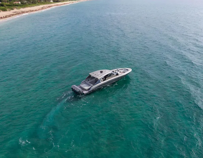  Yacht Photos Pics 2024 Mystic Powerboats M5200 cruising on clear blue ocean near coastline.