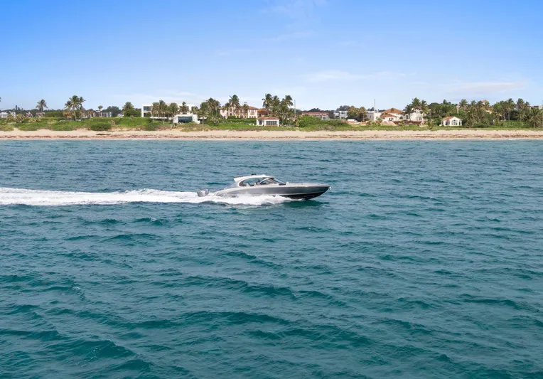  Yacht Photos Pics 2024 Mystic Powerboats M5200 cruising on ocean near tropical shoreline.