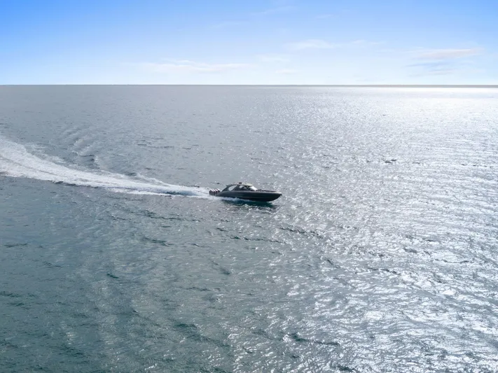  Yacht Photos Pics 2024 Mystic Powerboats M5200 cruising on open water under clear blue sky.