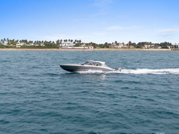  Yacht Photos Pics 2024 Mystic Powerboats M5200 cruising on open water near a coastal landscape.