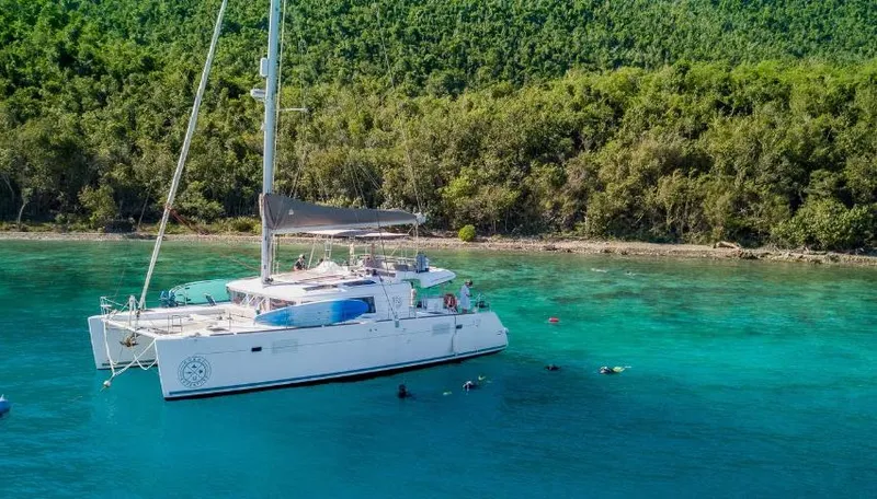 Great Adventure Yacht Photos Pics 2014 Lagoon 450 catamaran anchored in turquoise waters near lush green shoreline.