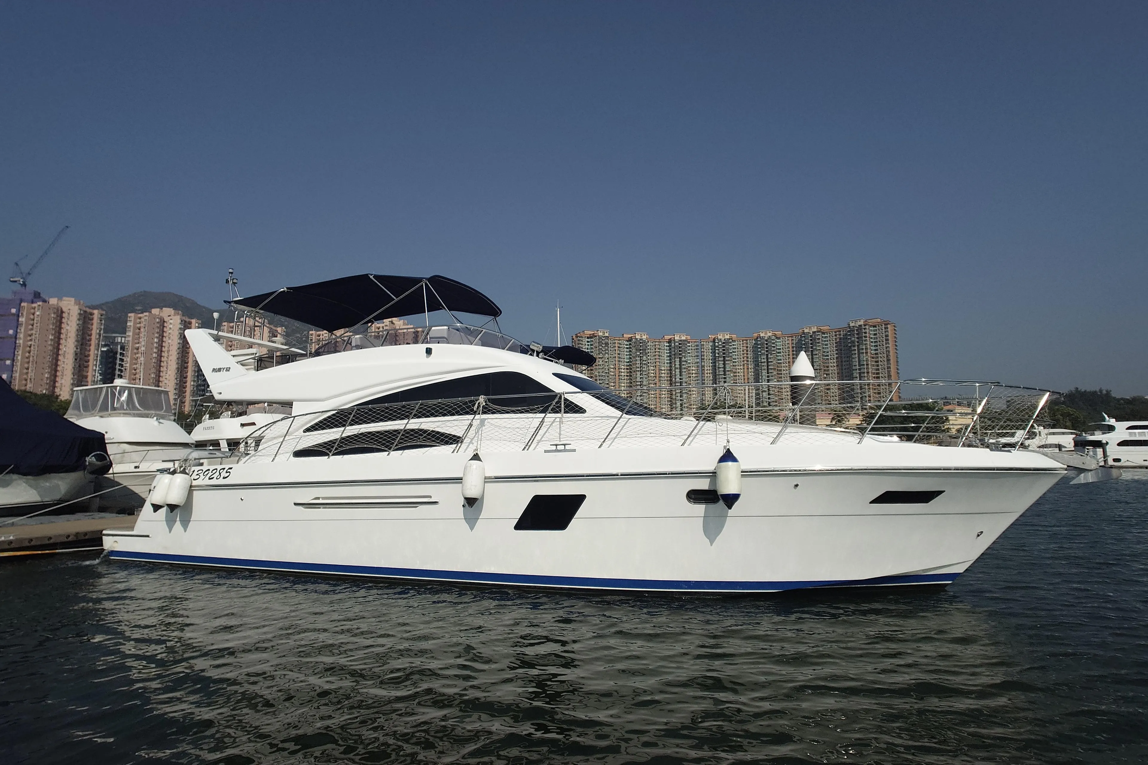 Luxury Ruby 52 yacht from 2009 docked in a marina with cityscape background.