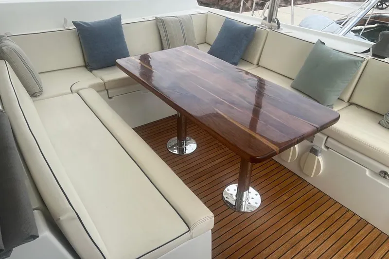 Queen Butterfly Yacht Photos Pics Luxurious seating area on a 2006 Lagoon 440 yacht with wooden table and cushions.