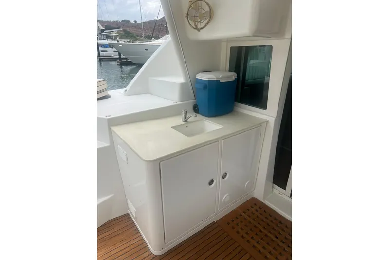 Queen Butterfly Yacht Photos Pics Outdoor sink area on 2006 Lagoon 440 yacht with blue cooler and wooden flooring.