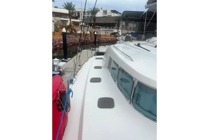 Queen Butterfly Yacht Photos Pics 2006 Lagoon 440 catamaran docked at marina with palm trees and modern buildings.