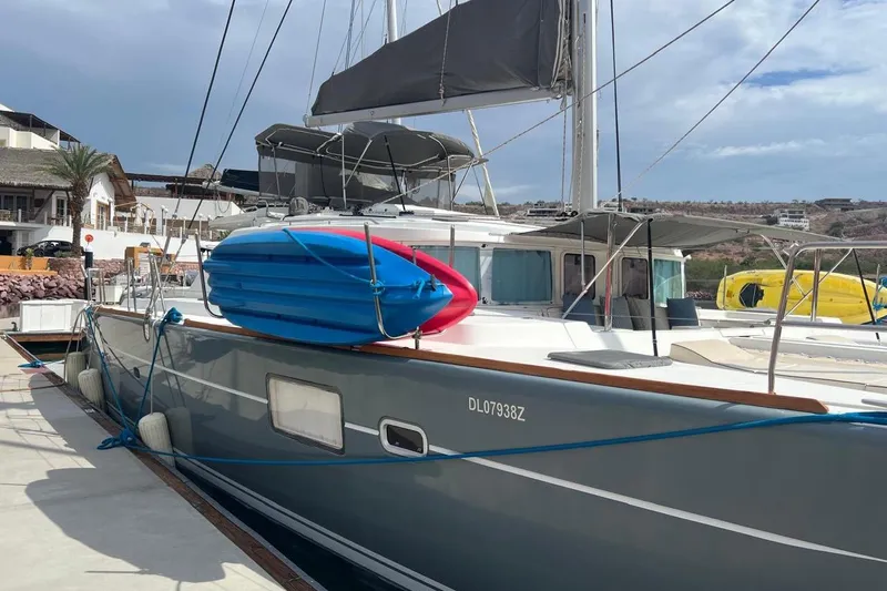 Queen Butterfly Yacht Photos Pics 2006 Lagoon 440 catamaran docked with kayaks on deck, under a cloudy sky.