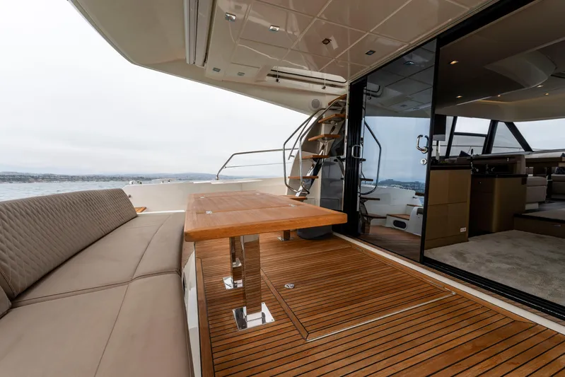 Seeworthy Yacht Photos Pics Luxurious 2018 Prestige 560 yacht deck with seating and wooden table, overlooking serene waters.
