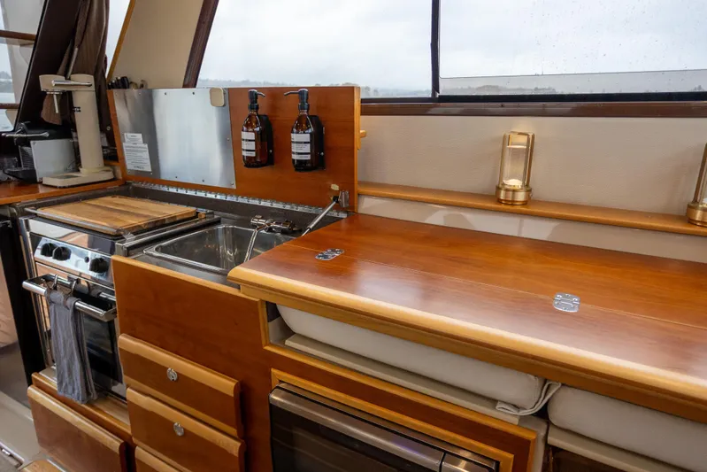 Halcyon Yacht Photos Pics Interior of 2016 Cutwater 30 CB boat featuring a compact kitchen with wooden cabinetry.