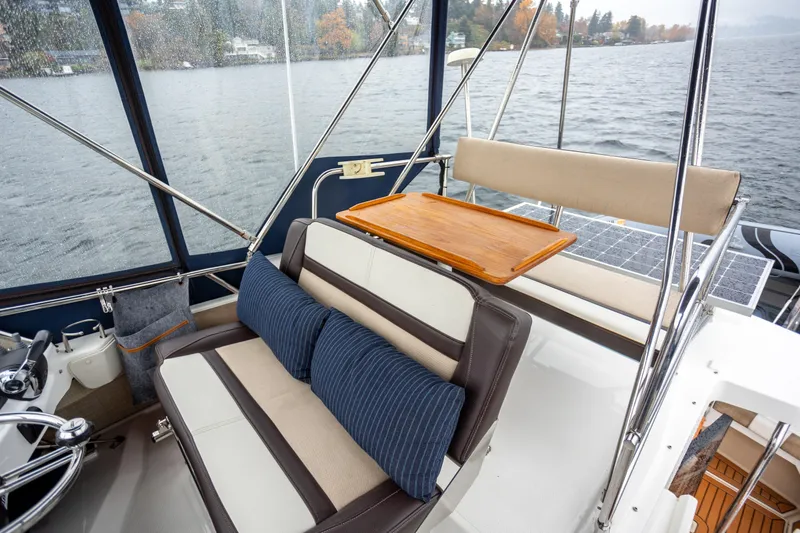 Halcyon Yacht Photos Pics 2016 Cutwater 30 CB boat interior with cushioned seating and wooden table on a lake.