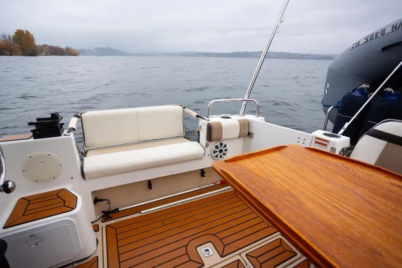 Halcyon Yacht Photos Pics 2016 Cutwater 30 CB boat interior with wooden deck and seating, overlooking a calm lake.