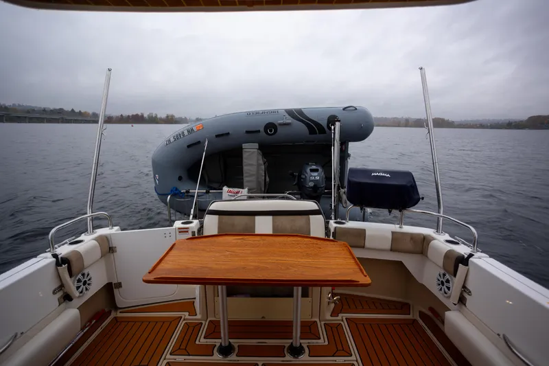 Halcyon Yacht Photos Pics 2016 Cutwater 30 CB boat interior with wooden table and inflatable dinghy on water.