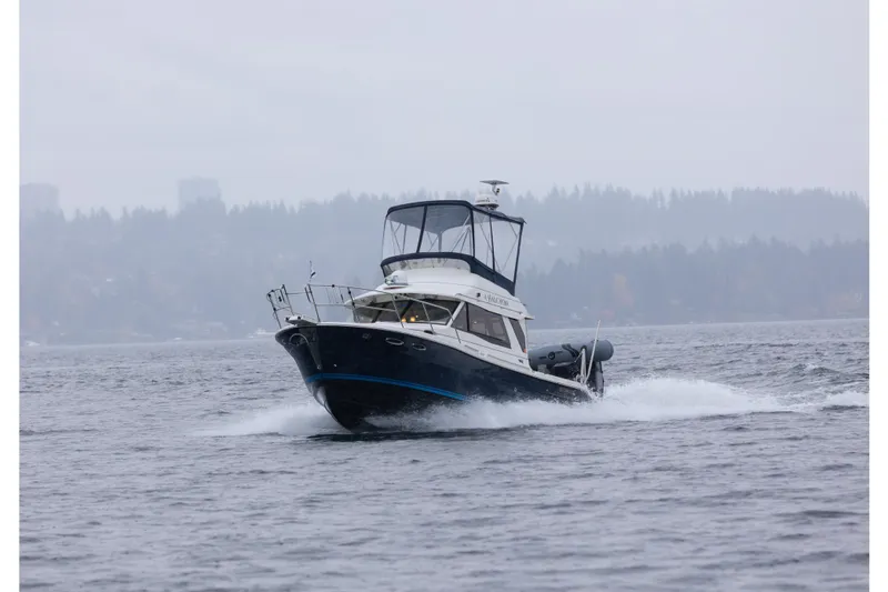 Halcyon Yacht Photos Pics 2016 Cutwater 30 CB cruising on a misty lake with forested background.