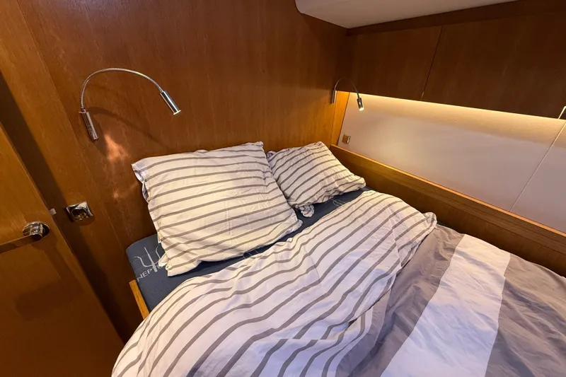 Pau Hana Yacht Photos Pics Cozy cabin interior of 2019 Nautor Swan 54 yacht with striped bedding and reading lights.