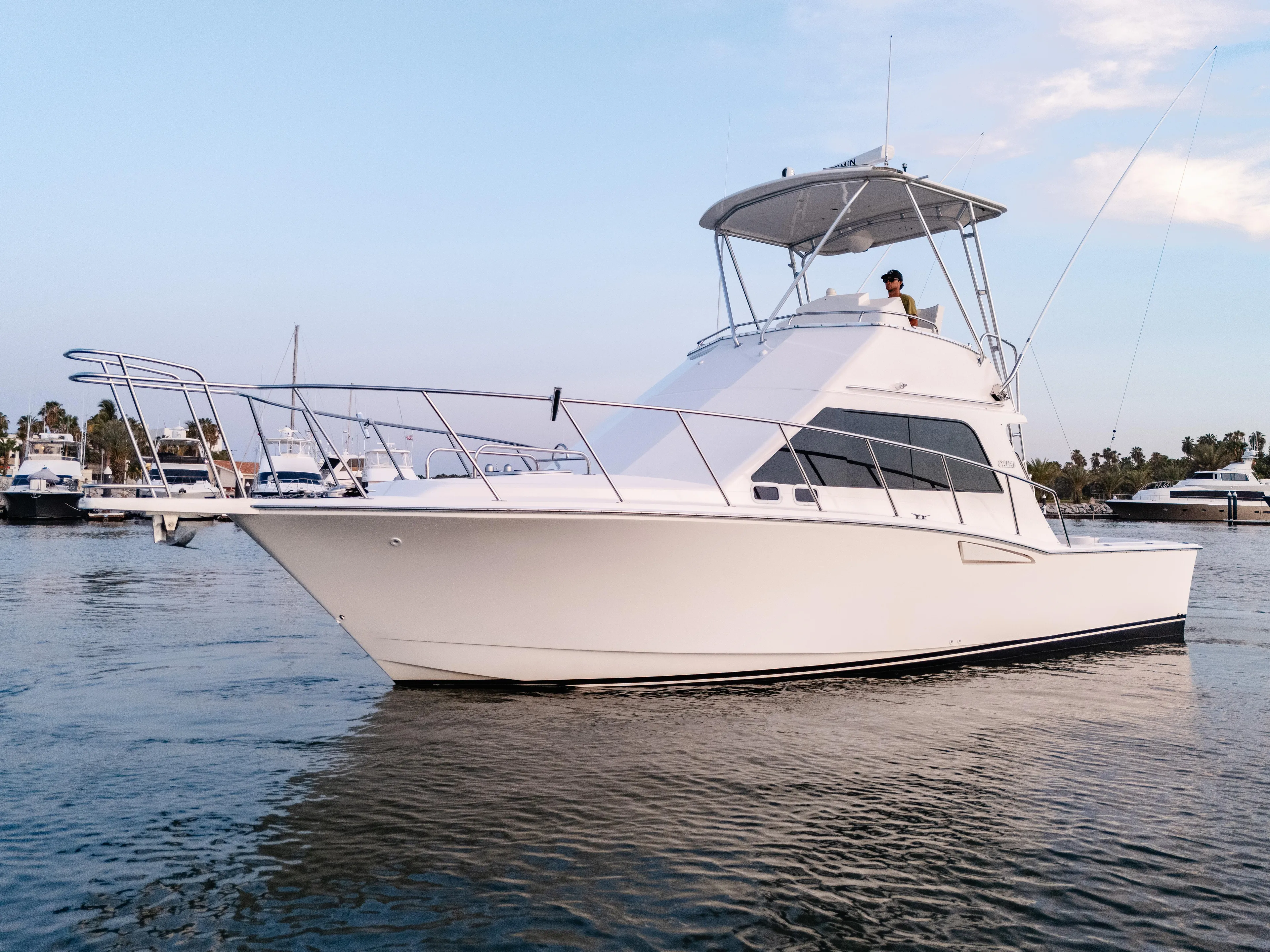 More Good Yacht Photos Pics 2002 Cabo 35 Flybridge yacht cruising in a serene marina setting.