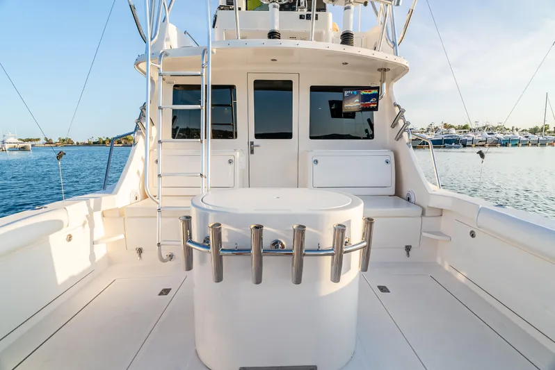 More Good Yacht Photos Pics 2002 Cabo 35 Flybridge boat deck with fishing rod holders and ladder, docked by the water.