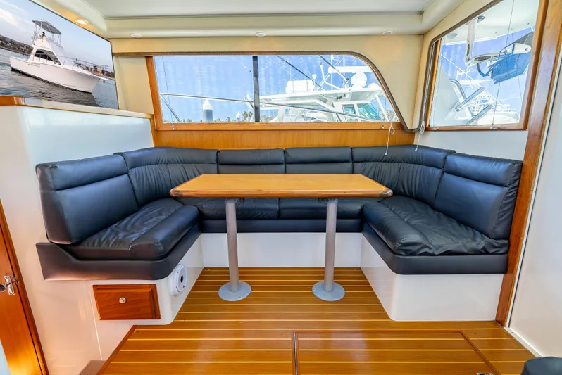 More Good Yacht Photos Pics Interior of 2002 Cabo 35 Flybridge with leather seating and wooden table.