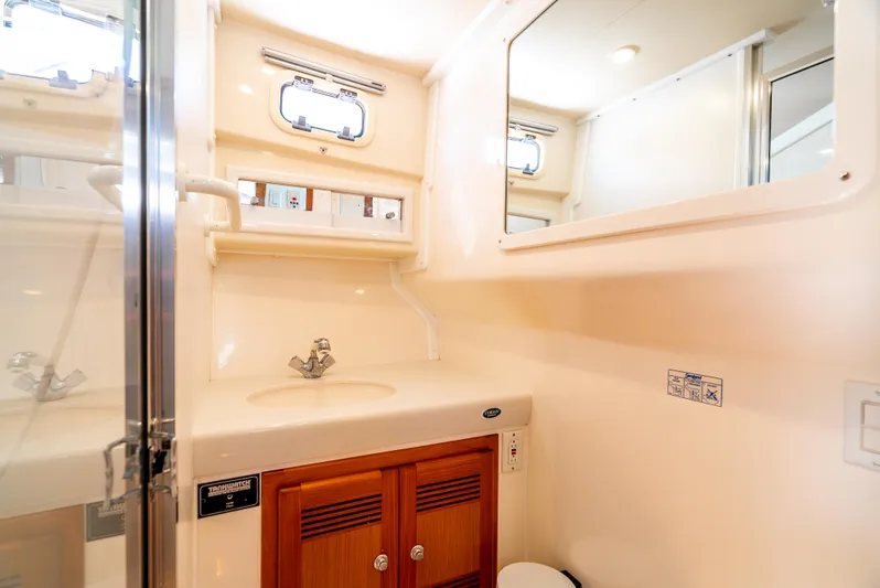 More Good Yacht Photos Pics 2002 Cabo 35 Flybridge bathroom with sink, mirror, and wooden cabinet.