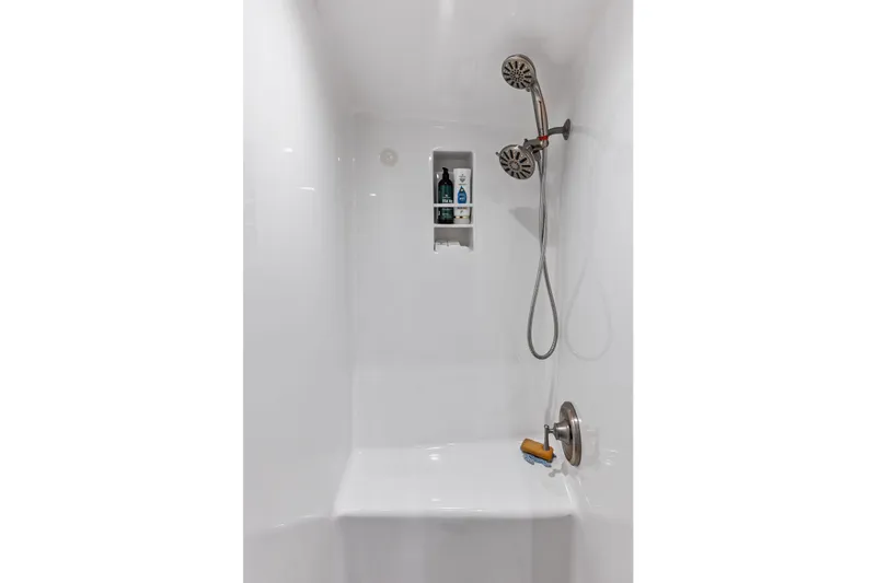 Knot Haulin Yacht Photos Pics Modern white shower with dual showerheads and built-in shelf, featuring toiletries.