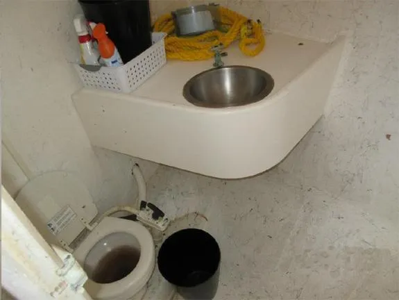  Yacht Photos Pics Small boat bathroom with toilet, sink, cleaning supplies, and yellow rope. Newton 46 Dive Special, 2004.