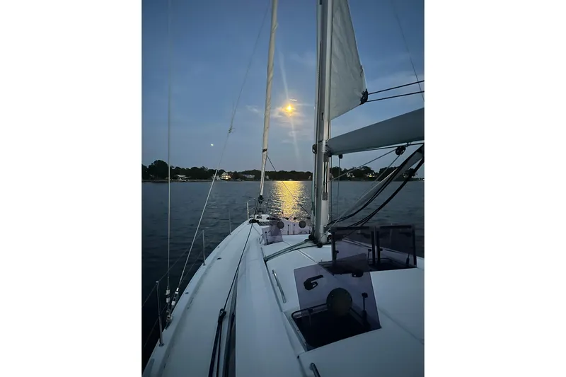 Recovery Room Yacht Photos Pics Sailing on a 2019 Jeanneau 51 yacht at sunset, calm waters reflecting moonlight.