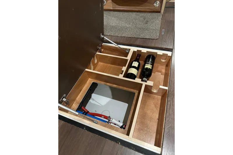 Recovery Room Yacht Photos Pics Hidden storage compartment in 2019 Jeanneau 51 yacht with wine bottles and utility access.