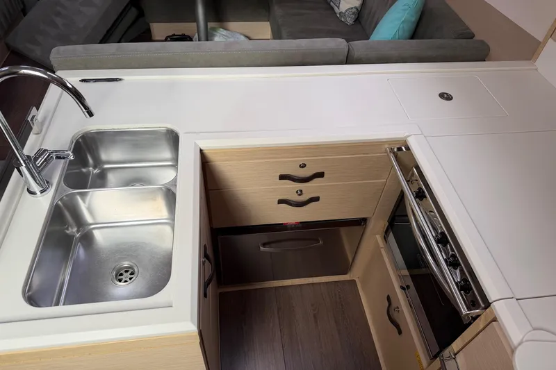 Recovery Room Yacht Photos Pics Modern kitchen area in a 2019 Jeanneau 51 yacht with stainless steel sink and stove.