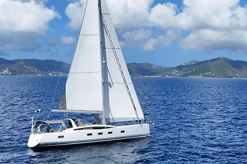 Miss Fiona Yacht Photos Pics 2020 Jeanneau 64 sailing yacht on open sea with scenic mountain backdrop.