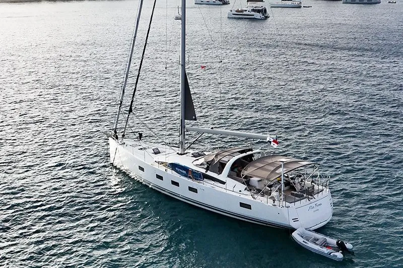 Miss Fiona Yacht Photos Pics 2020 Jeanneau 64 yacht anchored in calm waters with a small dinghy.