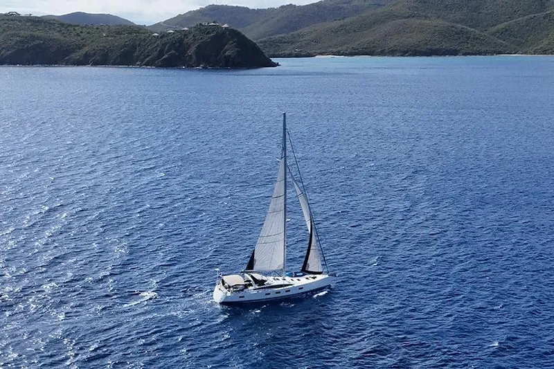 Miss Fiona Yacht Photos Pics 2020 Jeanneau 64 sailing in clear blue waters near a scenic coastline.