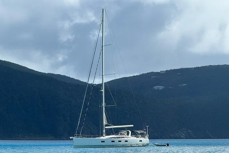 Miss Fiona Yacht Photos Pics 2020 Jeanneau 64 yacht anchored in serene blue waters with mountainous backdrop.