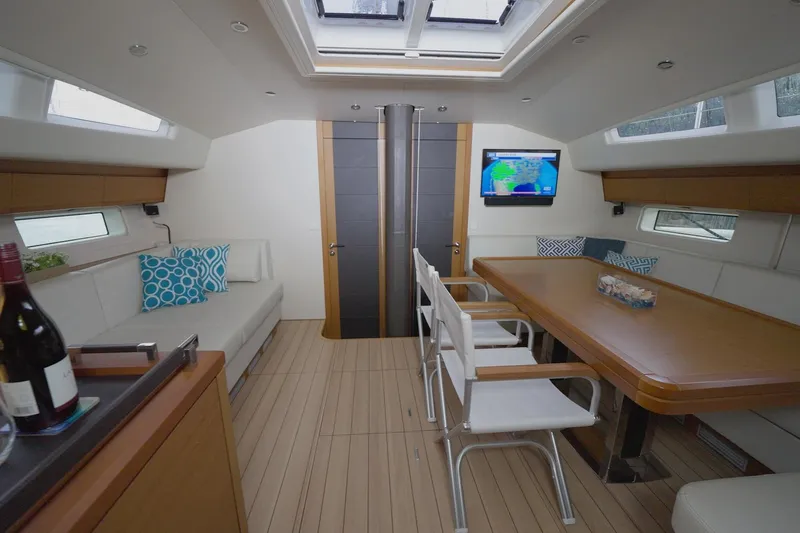 Miss Fiona Yacht Photos Pics Luxurious interior of 2020 Jeanneau 64 yacht with modern dining area and seating.