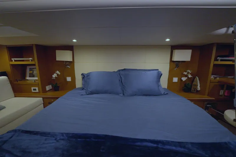 Miss Fiona Yacht Photos Pics Luxurious bedroom interior of 2020 Jeanneau 64 yacht with blue bedding and wooden accents.