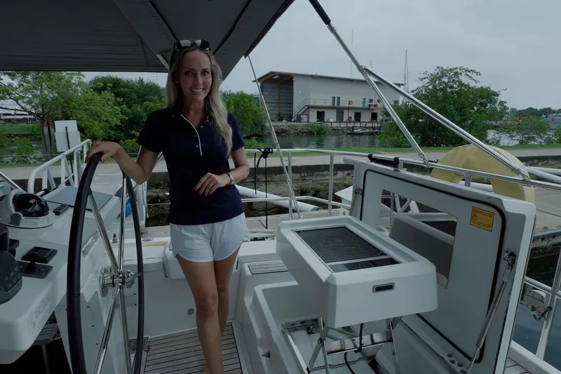 Miss Fiona Yacht Photos Pics Woman on Jeanneau 64 yacht, 2020 model, standing by the helm in a marina setting.