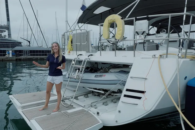 Miss Fiona Yacht Photos Pics Woman presenting a 2020 Jeanneau 64 yacht at a marina, showcasing its spacious deck.