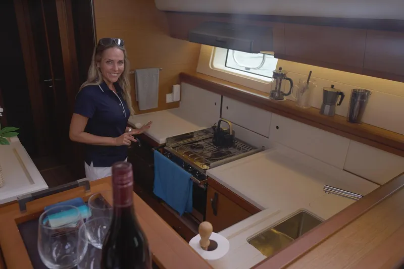 Miss Fiona Yacht Photos Pics Woman in Jeanneau 64 yacht kitchen, 2020 model, with wine and glasses on counter.