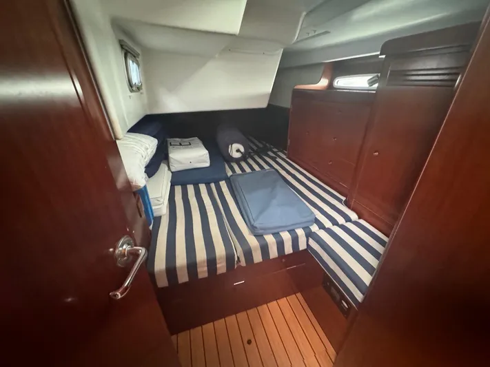 Kaleidoscope Yacht Photos Pics Cozy cabin interior of 2004 Beneteau First 47.7 with striped bedding and wooden finishes.