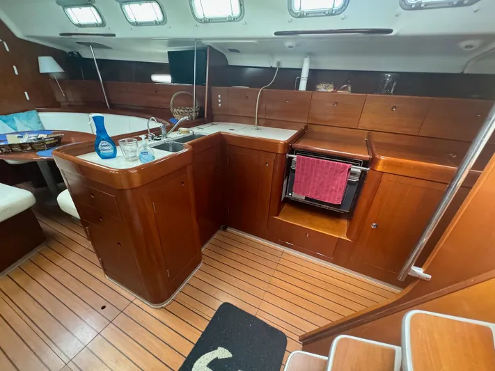 Kaleidoscope Yacht Photos Pics Interior of 2004 Beneteau First 47.7 yacht, featuring a wooden kitchen and seating area.