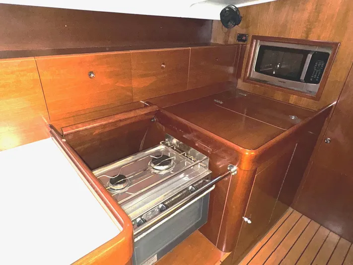 Kaleidoscope Yacht Photos Pics Beneteau First 47.7 2004 yacht kitchen with stove, microwave, and wooden cabinetry.