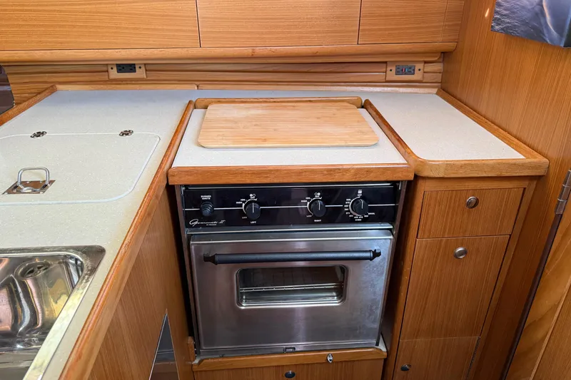 Magic Yacht Photos Pics Galley kitchen in 2011 Catalina 355 sailboat with stove, sink, and wooden cabinetry.
