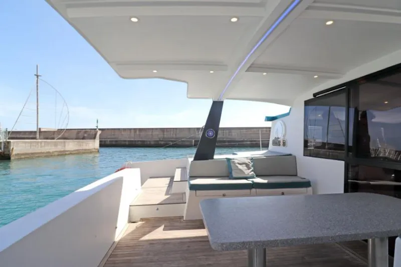  Yacht Photos Pics Modern Luna 47 yacht deck with seating and table, docked by a calm harbor.