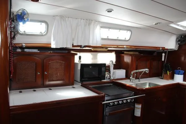  Yacht Photos Pics Interior of 1997 Beneteau Oceanis 461 yacht kitchen with wood cabinetry and modern appliances.