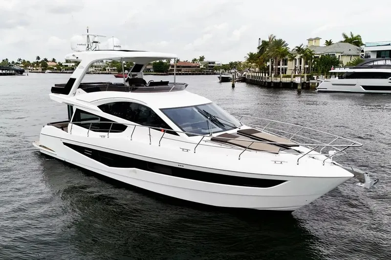 Bugsy Yacht Photos Pics 2020 Galeon 550 Fly yacht cruising on a calm waterway, surrounded by luxury homes.