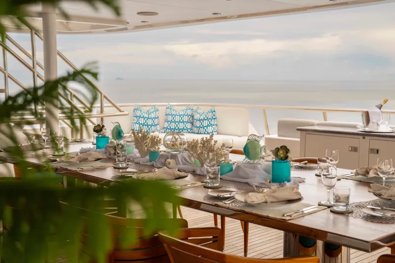 Dream Yacht Photos Pics Luxurious yacht dining setup with ocean view, featuring elegant tableware and blue accents. Abeking & Rasmussen 6430, 2001.
